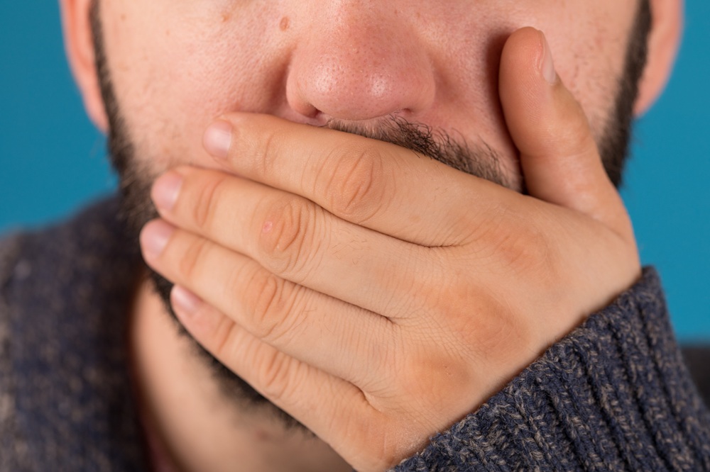 Closeup of a man covering his mouth with a hand